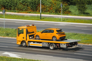 Yellow car being transported on flatbed truck